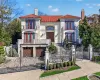Mediterranean / spanish house with a chimney, a gate, a fenced front yard, a balcony, and stucco siding Mediterranean / spanish house with a chimney, a gate, a fenced front yard, a balcony, and stucco siding