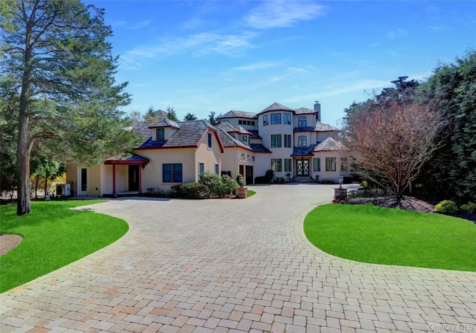 View of front of home featuring a front yard, stucco siding, curved driveway, and a chimney View of front of home featuring a front yard, stucco siding, curved driveway, and a chimney