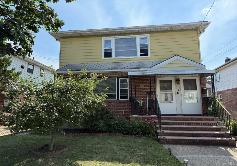 View of front facade featuring brick siding, a high end roof, and a front yard View of front facade featuring brick siding, a high end roof, and a front yard