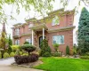 View of front of property featuring a front yard, brick siding, and a balcony View of front of property featuring a front yard, brick siding, and a balcony