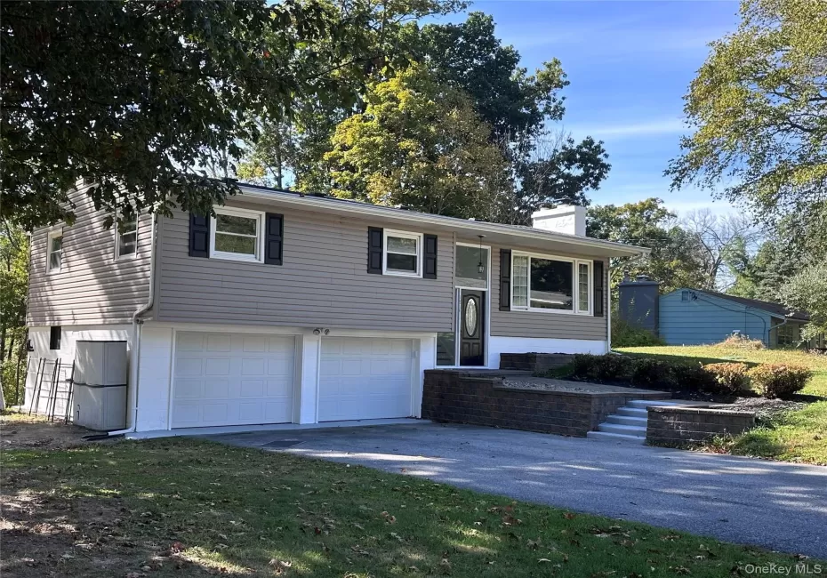 Bi-level home with a chimney, driveway, and an attached garage Bi-level home with a chimney, driveway, and an attached garage