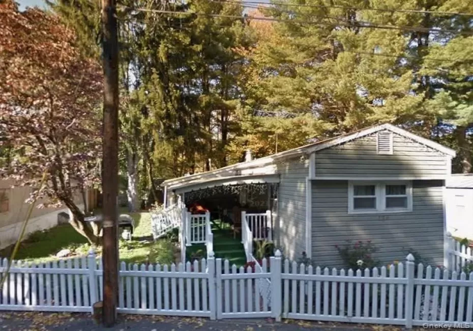 Single-story residence featuring light gray siding and a white picket fence Single-story residence featuring light gray siding and a white picket fence