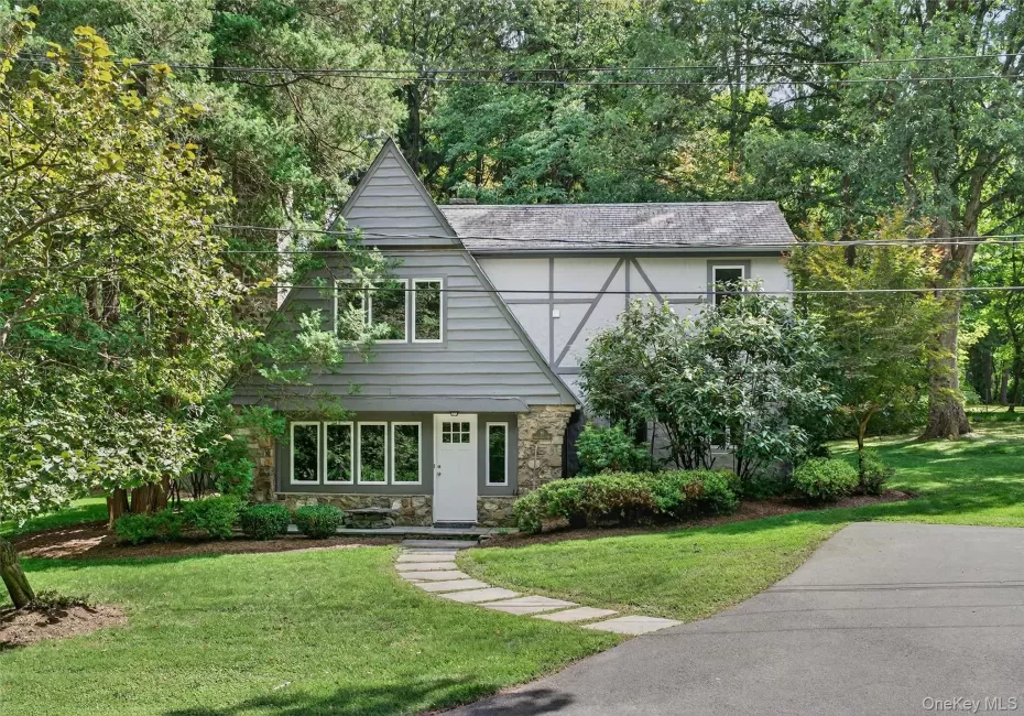 Tudor style carriage house with stone siding, a front lawn, and stucco siding Tudor style carriage house with stone siding, a front lawn, and stucco siding