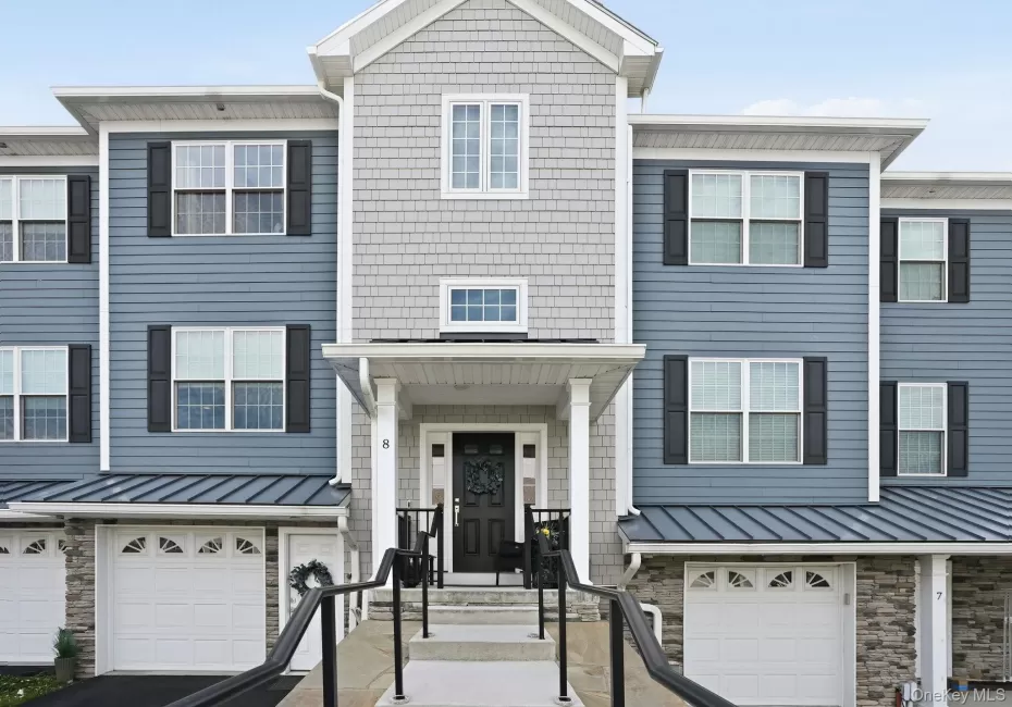 Townhome exterior featuring varied siding materials, stone accents, and a covered entry porch Townhome exterior featuring varied siding materials, stone accents, and a covered entry porch