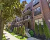 Brick exterior multifamily building featuring multiple balconies, individual ground-level entryways, mature landscaping, and an ornate street lamp Brick exterior multifamily building featuring multiple balconies, individual ground-level entryways, mature landscaping, and an ornate street lamp