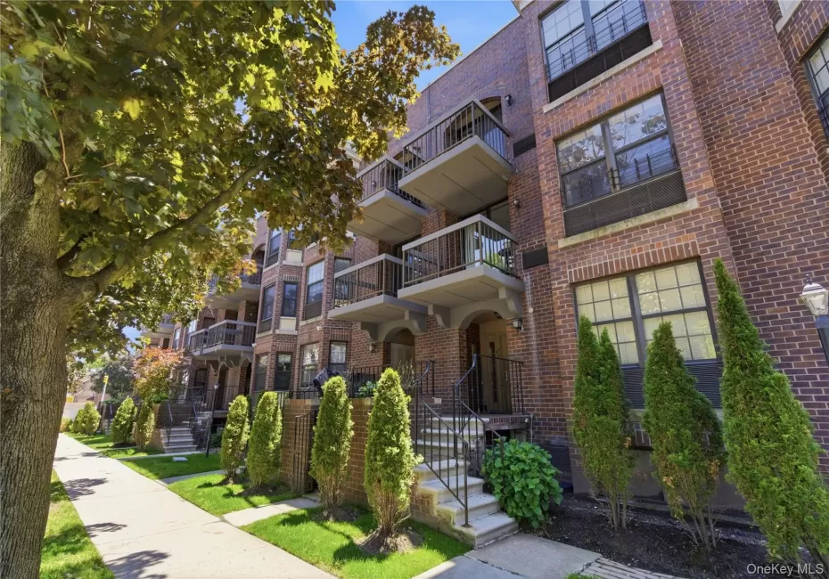 Brick exterior multifamily building featuring multiple balconies, individual ground-level entryways, mature landscaping, and an ornate street lamp Brick exterior multifamily building featuring multiple balconies, individual ground-level entryways, mature landscaping, and an ornate street lamp