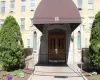 Building entrance featuring a prominent arched doorway, double wooden entry doors, and a brown canvas awning Building entrance featuring a prominent arched doorway, double wooden entry doors, and a brown canvas awning