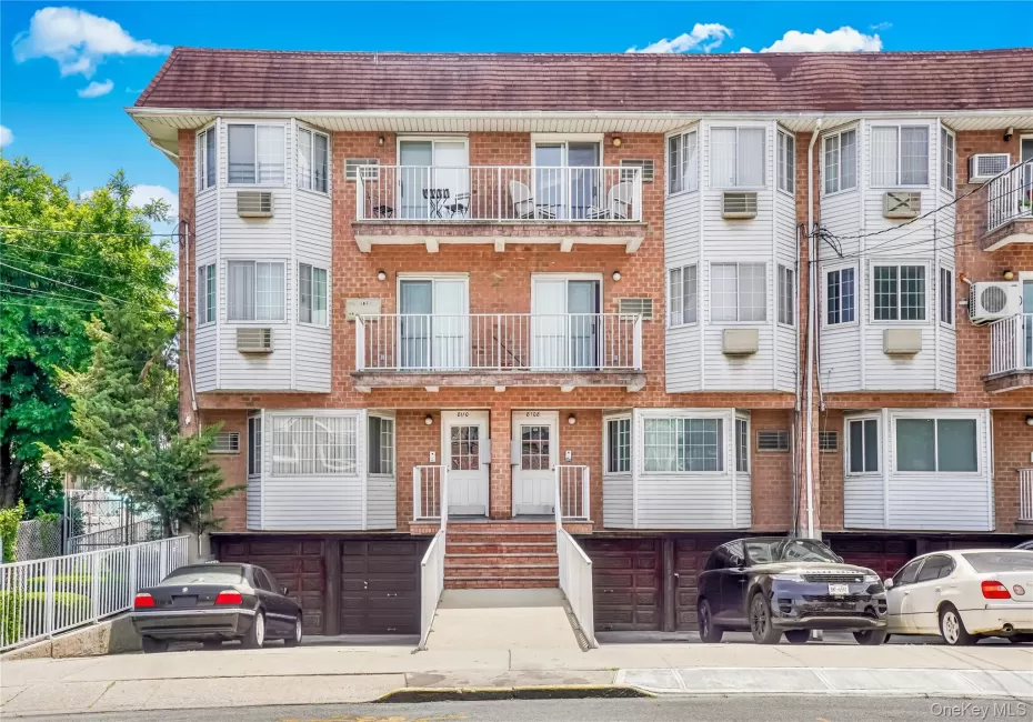 Multi-unit brick building featuring white vinyl siding and multiple balconies with white railings Multi-unit brick building featuring white vinyl siding and multiple balconies with white railings