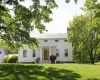 White siding exterior featuring a covered porch with white columns, a natural wood front door, and a metal roof White siding exterior featuring a covered porch with white columns, a natural wood front door, and a metal roof