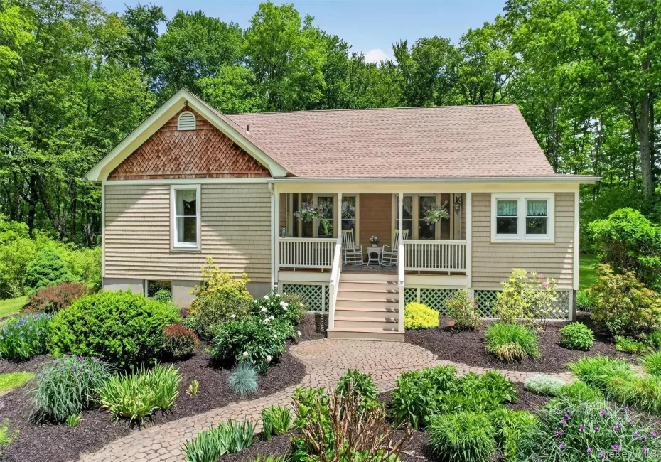 Bungalow-style home featuring light tan siding, a front porch, and a shingled roof Bungalow-style home featuring light tan siding, a front porch, and a shingled roof