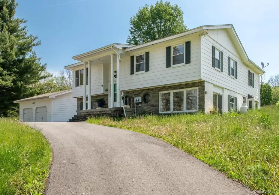 Upper level of residence featuring a two-car detached garage, and a paved driveway Upper level of residence featuring a two-car detached garage, and a paved driveway