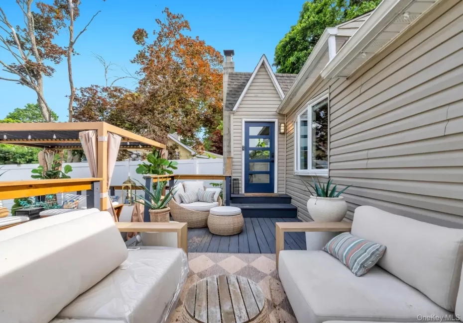 Exterior deck space featuring dark grey wood-finish flooring, a contemporary dark blue entry door with frosted glass panels, and horizontal siding Exterior deck space featuring dark grey wood-finish flooring, a contemporary dark blue entry door with frosted glass panels, and horizontal siding