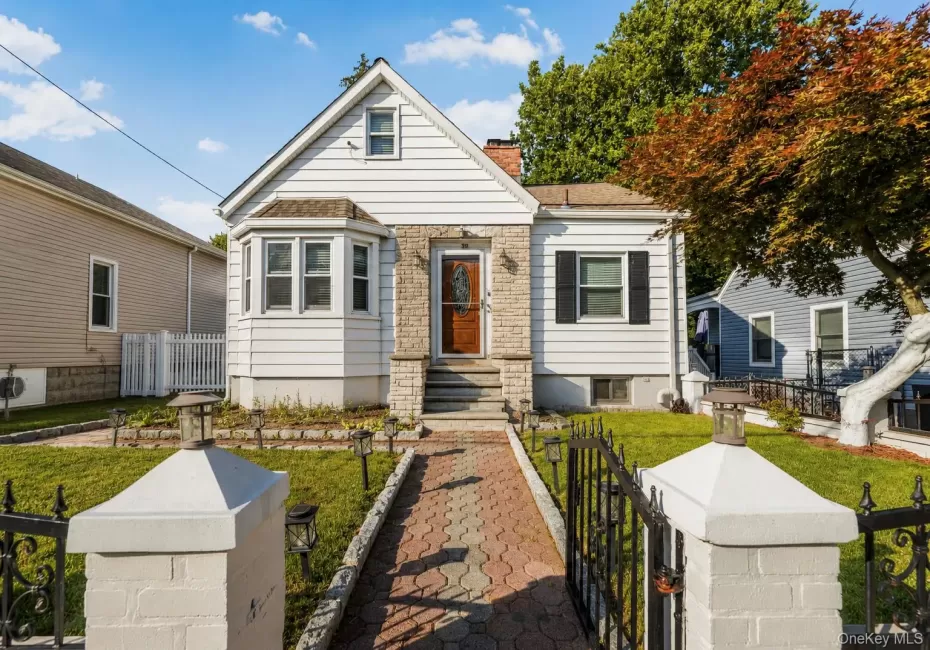 Charming facade featuring white siding, a bay window with multiple panes, and a prominent stone entryway Charming facade featuring white siding, a bay window with multiple panes, and a prominent stone entryway