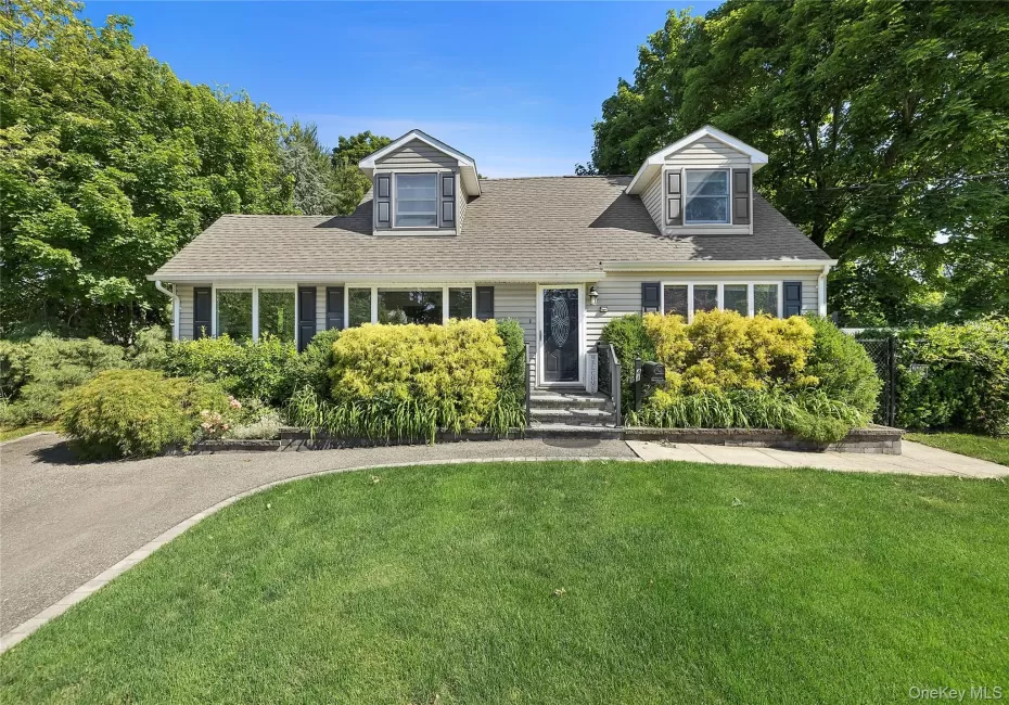 Traditional home exterior featuring light-colored siding, a dark roof, and two dormer windows Traditional home exterior featuring light-colored siding, a dark roof, and two dormer windows