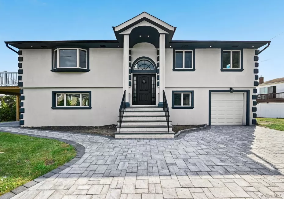 View of front of home with stucco siding, decorative driveway, and an attached garage View of front of home with stucco siding, decorative driveway, and an attached garage