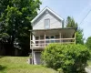 Gray siding exterior featuring a covered porch with a wood railing and exterior lighting. Gray siding exterior featuring a covered porch with a wood railing and exterior lighting.