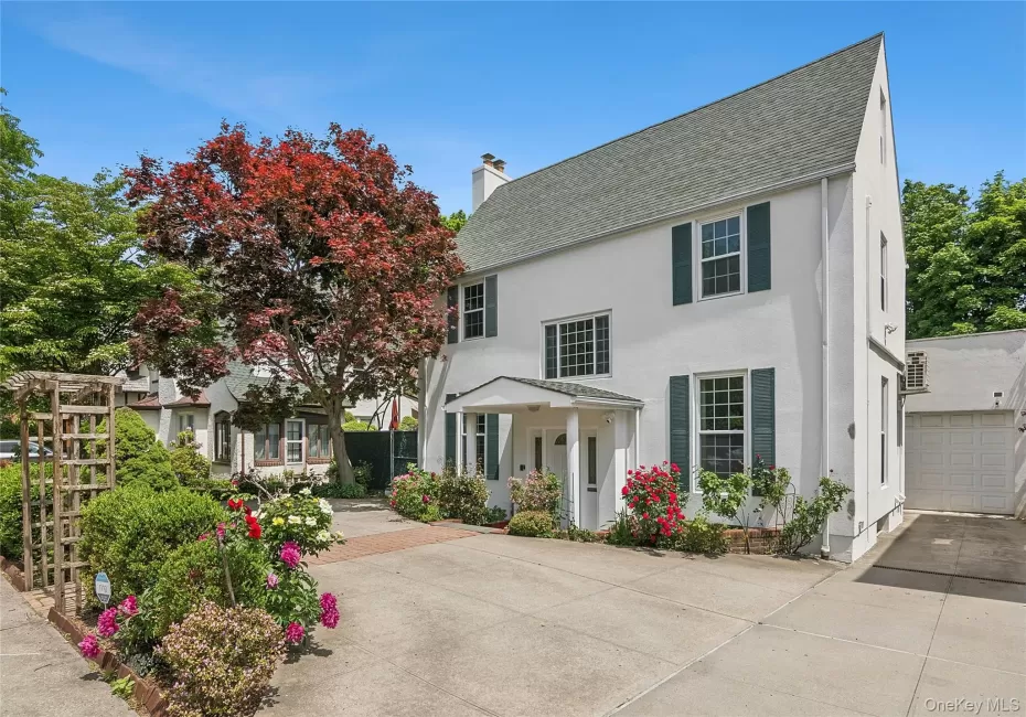 White stucco exterior with a prominent gabled roofline and dark green window shutters White stucco exterior with a prominent gabled roofline and dark green window shutters