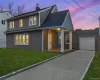 View of front facade featuring a front yard, driveway, a porch, a chimney, and roof with shingles View of front facade featuring a front yard, driveway, a porch, a chimney, and roof with shingles