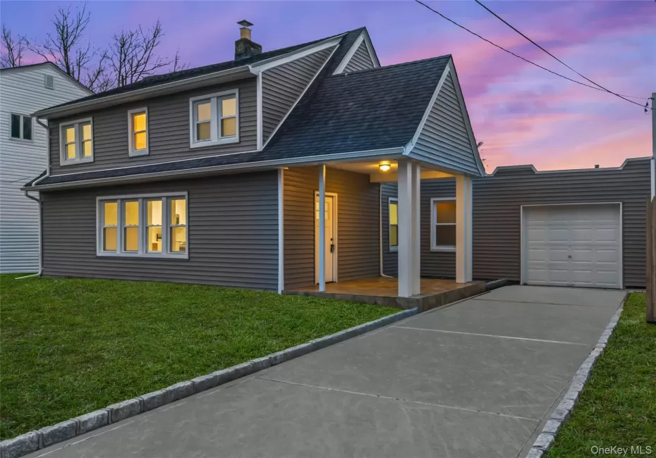 View of front facade featuring a front yard, driveway, a porch, a chimney, and roof with shingles View of front facade featuring a front yard, driveway, a porch, a chimney, and roof with shingles