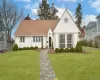 View of front facade with a chimney, a shingled roof, and a front lawn View of front facade with a chimney, a shingled roof, and a front lawn
