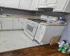 Kitchen featuring white cabinetry, a white range, a stainless steel faucet, and speckled countertops Kitchen featuring white cabinetry, a white range, a stainless steel faucet, and speckled countertops