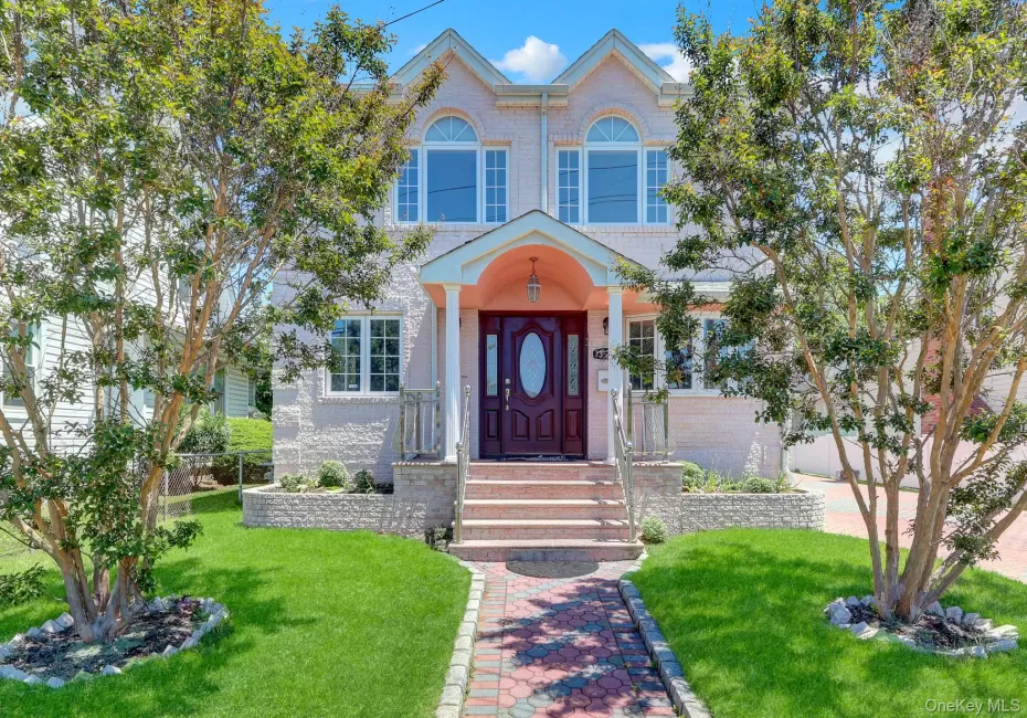 Residence featuring a textured light-colored facade, an arched entry portico, and a dark wood-finish front door with an oval glass insert Residence featuring a textured light-colored facade, an arched entry portico, and a dark wood-finish front door with an oval glass insert