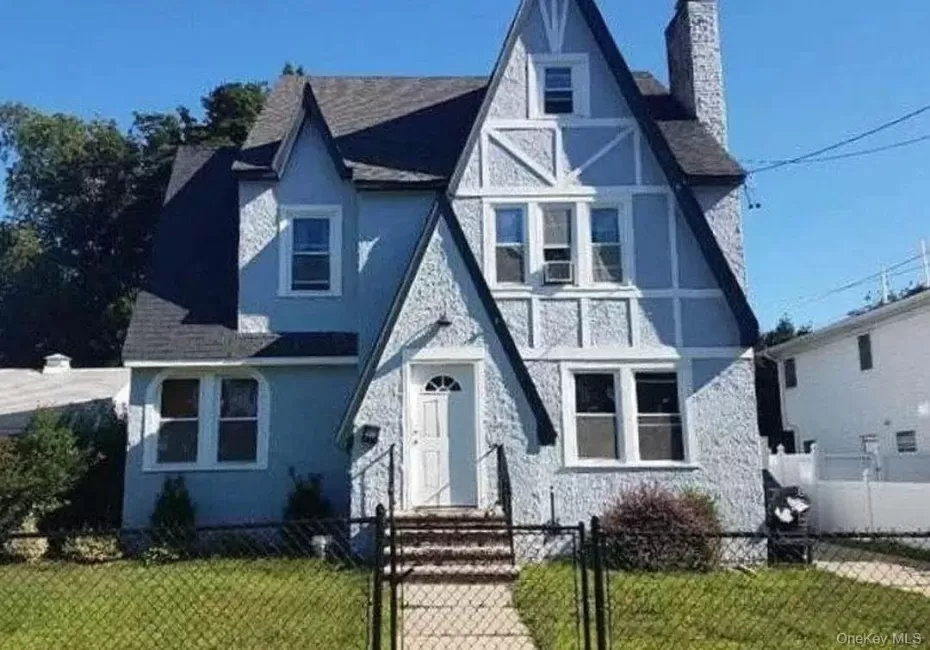 Distinctive Tudor Revival-style residence featuring a prominent front-facing gable and textured stucco siding Distinctive Tudor Revival-style residence featuring a prominent front-facing gable and textured stucco siding