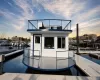 Two-story houseboat featuring white exterior siding with blue trim and black railings Two-story houseboat featuring white exterior siding with blue trim and black railings