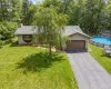 View of front of property featuring a front lawn, driveway, an attached garage, a chimney, and a shingled roof View of front of property featuring a front lawn, driveway, an attached garage, a chimney, and a shingled roof