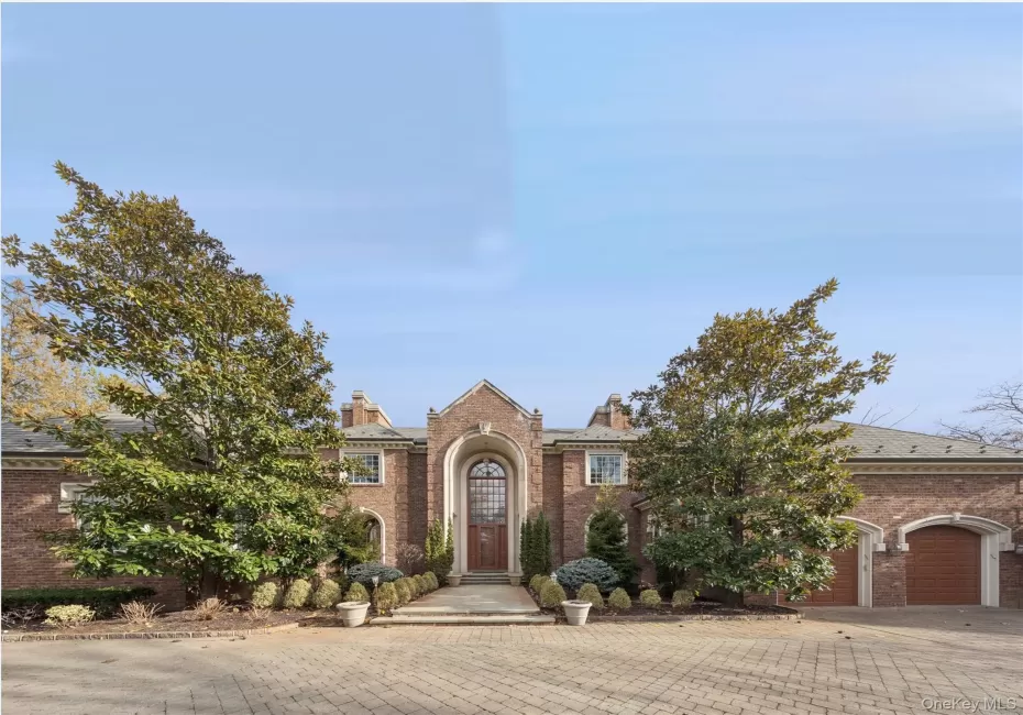 View of front of home with brick siding, driveway, a chimney, and a garage View of front of home with brick siding, driveway, a chimney, and a garage