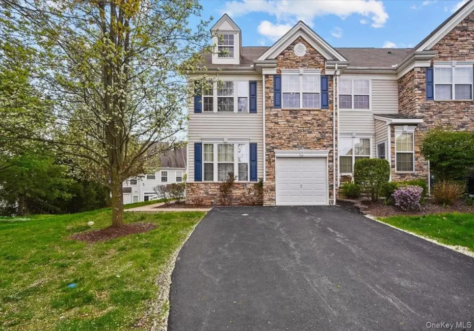Multi-level townhome featuring stone and siding facade, an integrated garage, and a paved driveway Multi-level townhome featuring stone and siding facade, an integrated garage, and a paved driveway