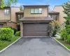 Two-story townhouse with a brown paneled garage door, asphalt driveway, and mature landscaping Two-story townhouse with a brown paneled garage door, asphalt driveway, and mature landscaping