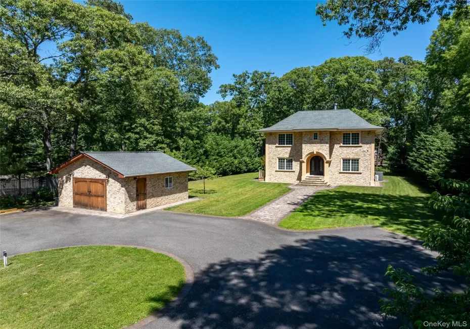 Stone-clad residence featuring a central arched entryway, multi-paned windows, and a dark shingle roof Stone-clad residence featuring a central arched entryway, multi-paned windows, and a dark shingle roof