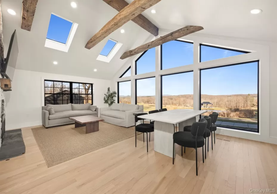 Living area featuring a skylight, light wood flooring, high vaulted ceiling, recessed lighting, and beamed ceiling Living area featuring a skylight, light wood flooring, high vaulted ceiling, recessed lighting, and beamed ceiling