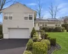 Split level home featuring an attached garage, driveway, a front yard, and roof mounted solar panels Split level home featuring an attached garage, driveway, a front yard, and roof mounted solar panels