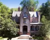 View of front facade featuring covered porch, brick siding, a chimney, and a high end roof View of front facade featuring covered porch, brick siding, a chimney, and a high end roof