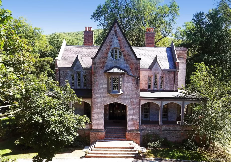 View of front facade featuring covered porch, brick siding, a chimney, and a high end roof View of front facade featuring covered porch, brick siding, a chimney, and a high end roof