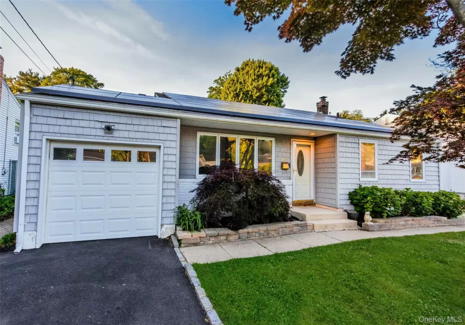 Ranch-style exterior featuring gray shake siding, a white panel garage door, and a white entry door with an oval glass insert Ranch-style exterior featuring gray shake siding, a white panel garage door, and a white entry door with an oval glass insert