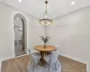 Dining area featuring a contemporary brass chandelier, wood-finish flooring, recessed ceiling lights, an arched entryway, and white baseboards Dining area featuring a contemporary brass chandelier, wood-finish flooring, recessed ceiling lights, an arched entryway, and white baseboards