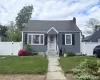 Charming residence featuring blue siding, a dark shingle roof, a brick chimney, and white privacy fencing Charming residence featuring blue siding, a dark shingle roof, a brick chimney, and white privacy fencing