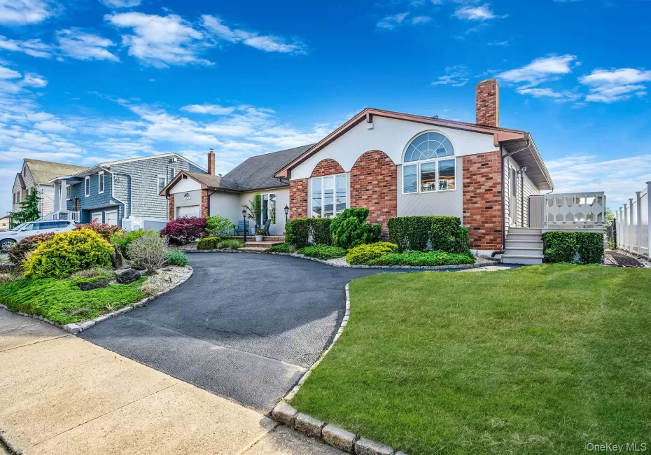 View of front facade featuring brick siding, a chimney, a front yard, and asphalt driveway View of front facade featuring brick siding, a chimney, a front yard, and asphalt driveway
