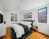 Bedroom with radiator heating unit, wood finished floors, and cooling unit Bedroom with radiator heating unit, wood finished floors, and cooling unit
