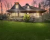 Back of house at dusk featuring a yard and a chimney Back of house at dusk featuring a yard and a chimney