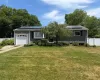 Ranch-style residence featuring grey siding, a front-facing garage with a white door, and a bay window Ranch-style residence featuring grey siding, a front-facing garage with a white door, and a bay window