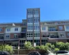 Multi-story residential building featuring a brick and siding exterior, expansive window panels, private balconies with black railings, and a prominent central glass-enclosed stairwell Multi-story residential building featuring a brick and siding exterior, expansive window panels, private balconies with black railings, and a prominent central glass-enclosed stairwell