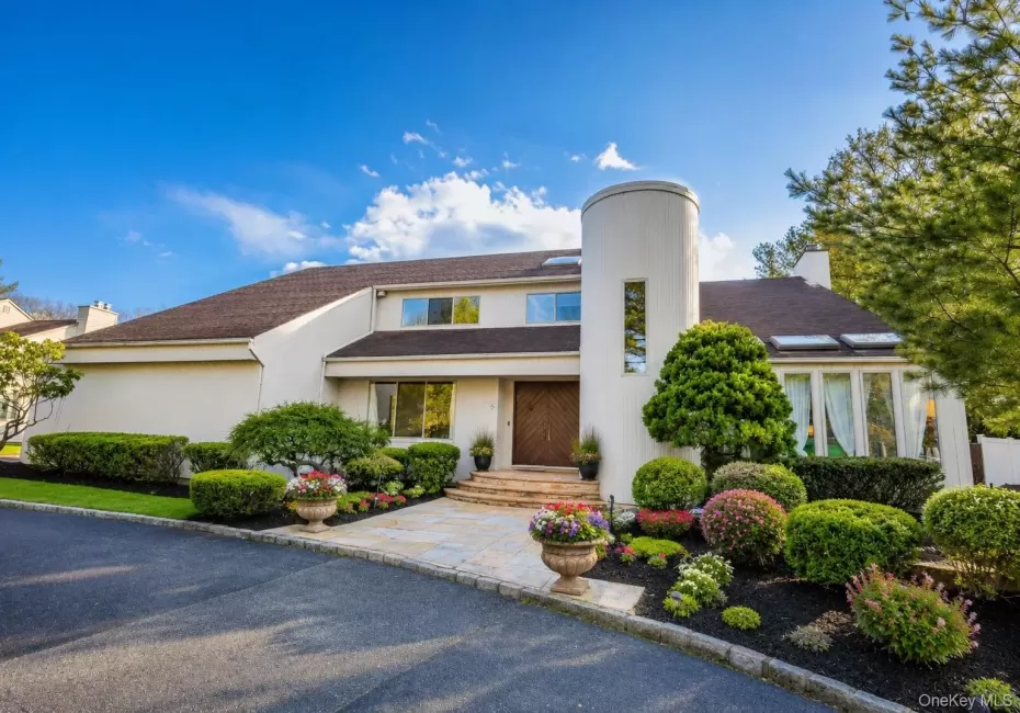 Contemporary stucco exterior featuring a prominent cylindrical tower with vertical window, double wooden entry doors, and a stone-paved walkway Contemporary stucco exterior featuring a prominent cylindrical tower with vertical window, double wooden entry doors, and a stone-paved walkway