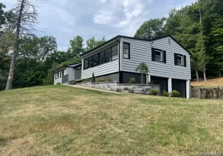 View of side of property featuring a garage and a yard View of side of property featuring a garage and a yard