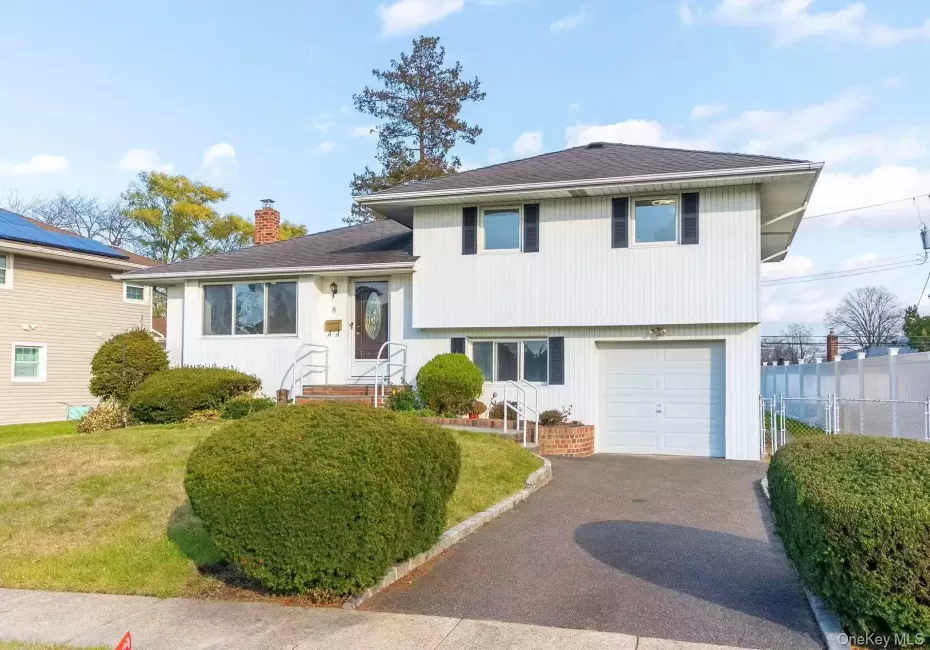 Tri-level home featuring a chimney, driveway, an attached garage, and roof with shingles Tri-level home featuring a chimney, driveway, an attached garage, and roof with shingles