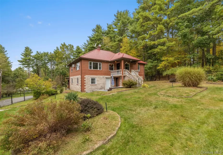 View of front of property featuring a chimney, stone siding, and view of scattered trees View of front of property featuring a chimney, stone siding, and view of scattered trees
