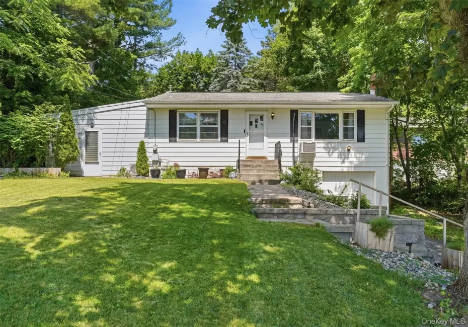 Split-level residence featuring white siding, dark shutters, and a prominent front entrance with stone steps Split-level residence featuring white siding, dark shutters, and a prominent front entrance with stone steps